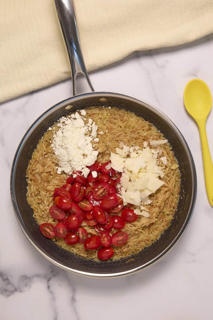 add the cherry tomatoes and the feta and parmesan cheeses