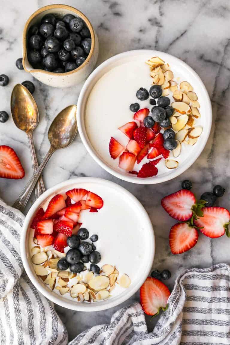 Bowls of high protein cottage cheese pudding served with strawberries, blueberries, and almond slices