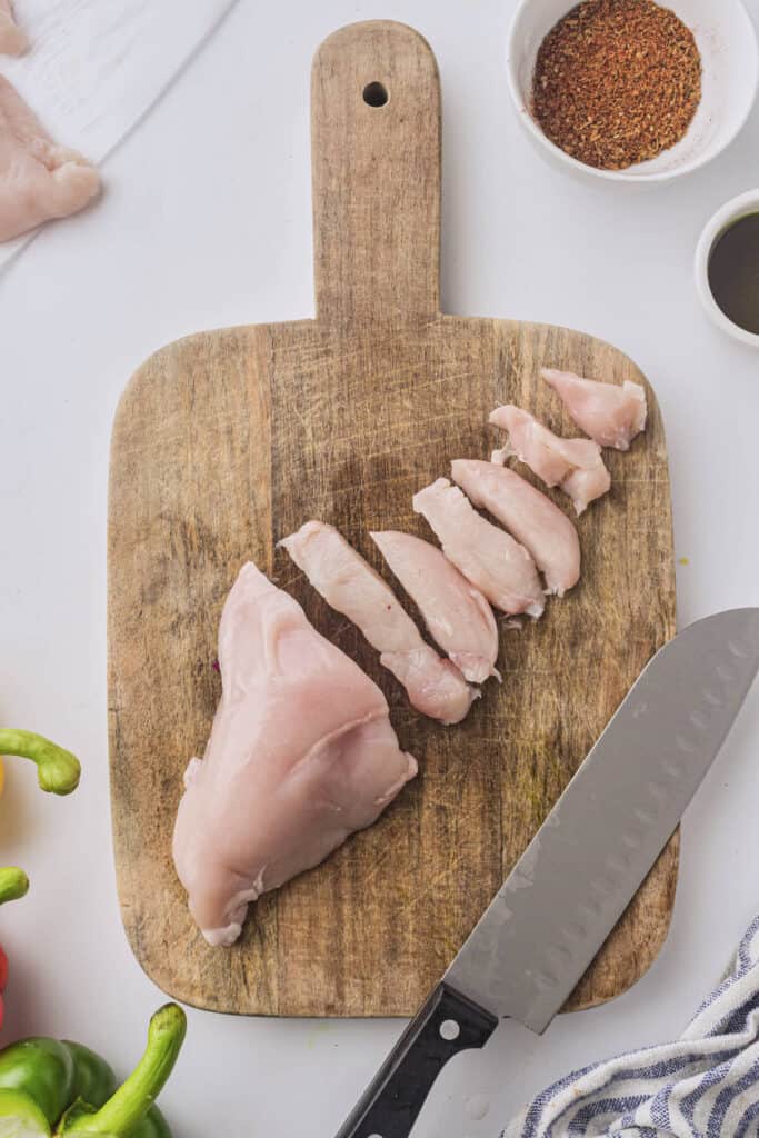 Cutting the chicken breast into strips on the cutting board