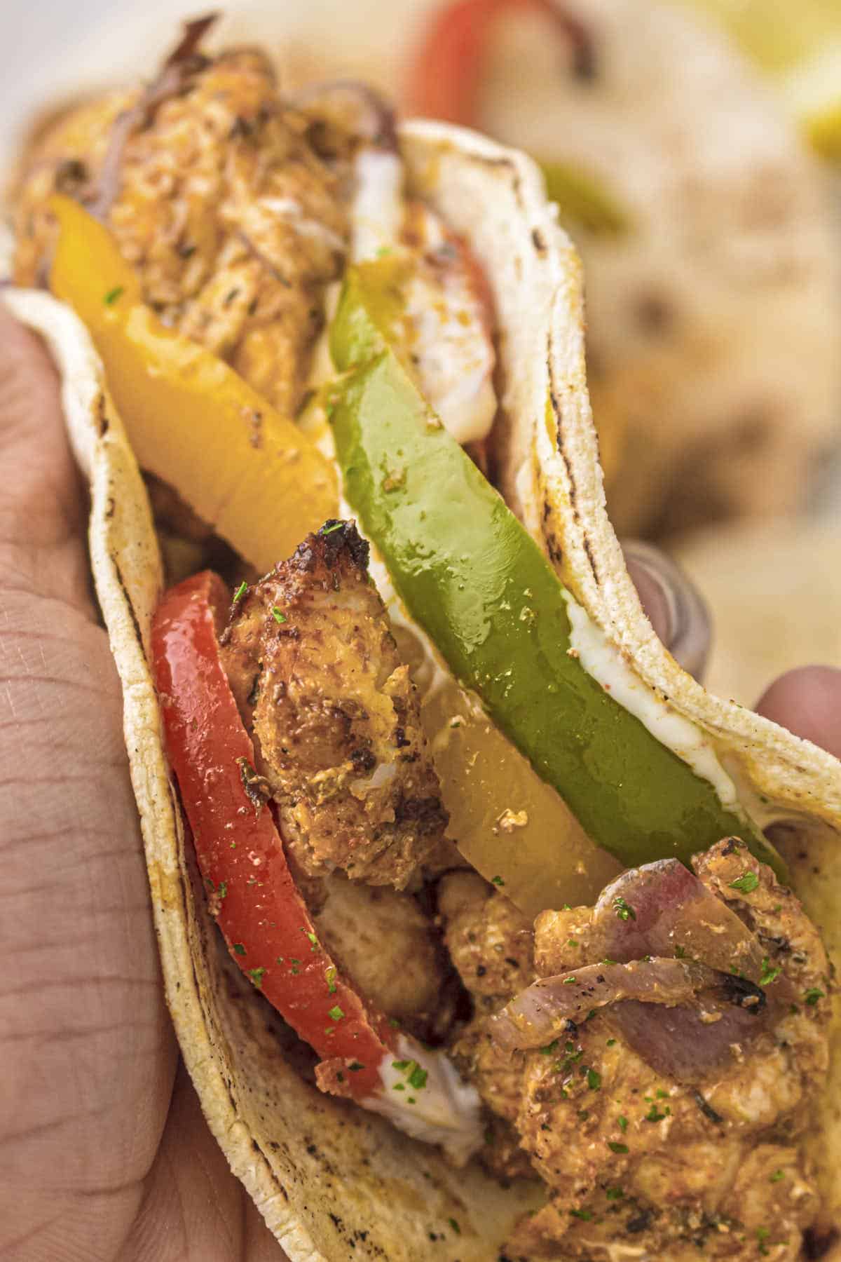 Hand held shot of the chicken fajitas with veggies in a tortilla