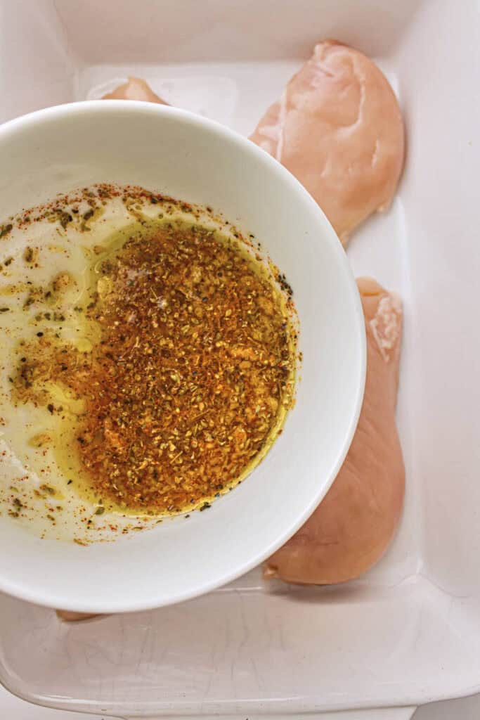 The marinade ready to be poured over the chicken breasts that are in a baking dish underneath