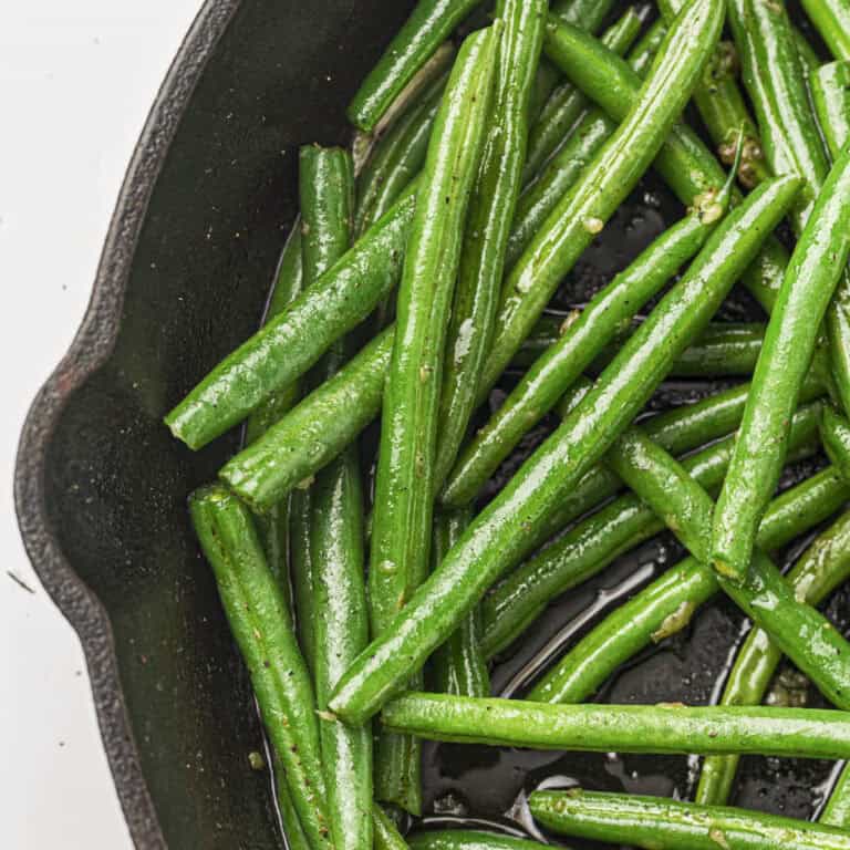 Garlic butter green beans from this recipe being seared in a cast iron pan