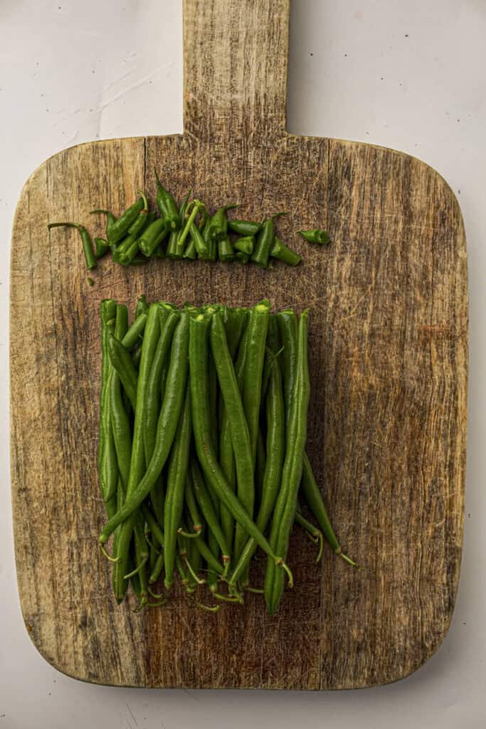 Green beans on a cutting board with their ends trimmed off one side