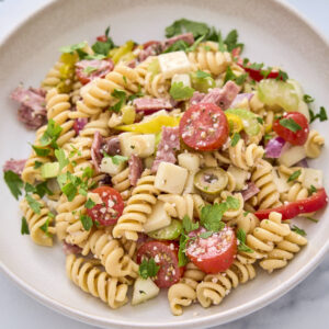 High protein pasta salad from this recipe shown on a plate garnished with some chopped parsley