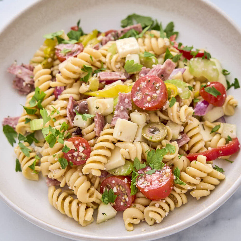 High protein pasta salad from this recipe shown on a plate garnished with some chopped parsley