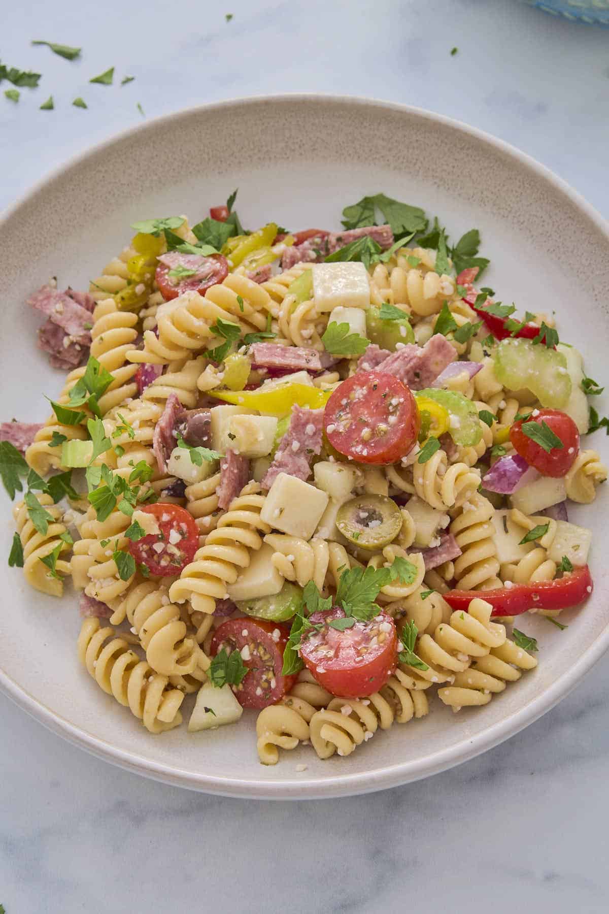 Hero shot of some of the pasta salad from this recipe served on a plate and garnished with some chopped parsley