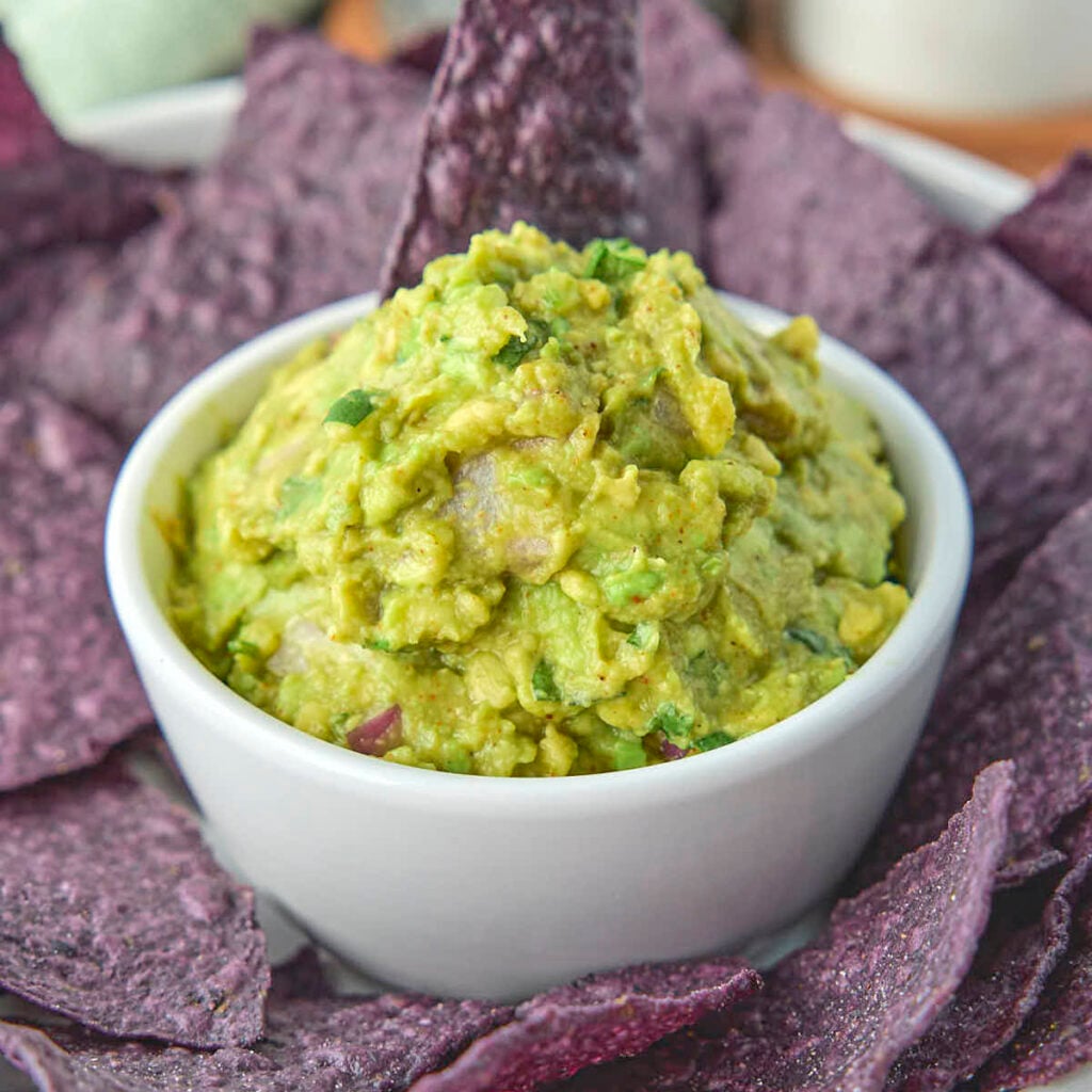 Keto guacamole from this recipe surrounded by some organic blue corn tortilla chips