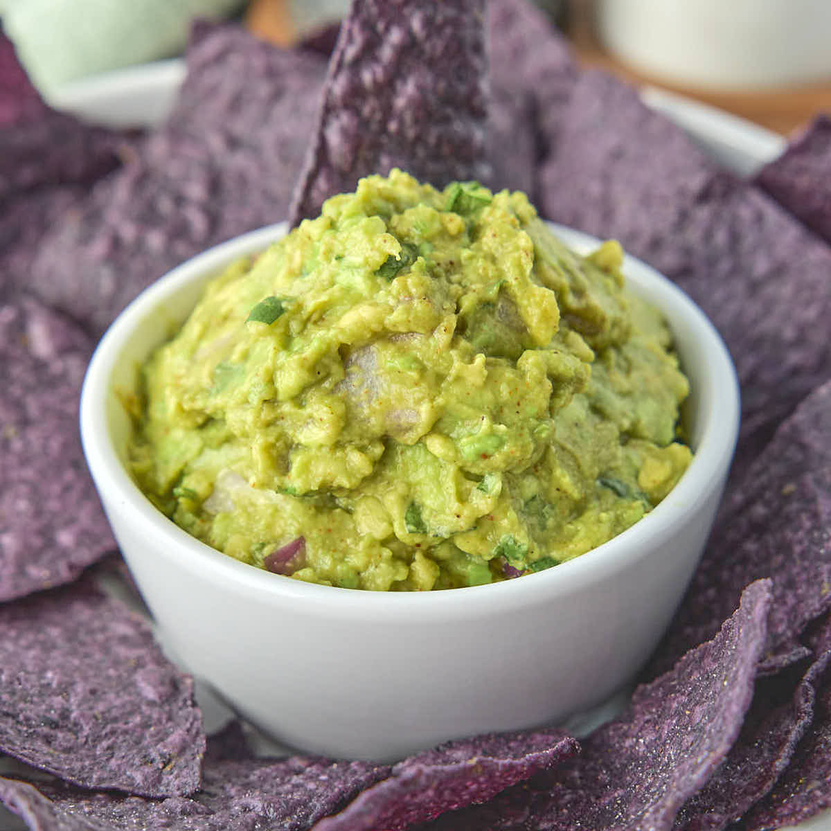 Keto guacamole from this recipe surrounded by some organic blue corn tortilla chips