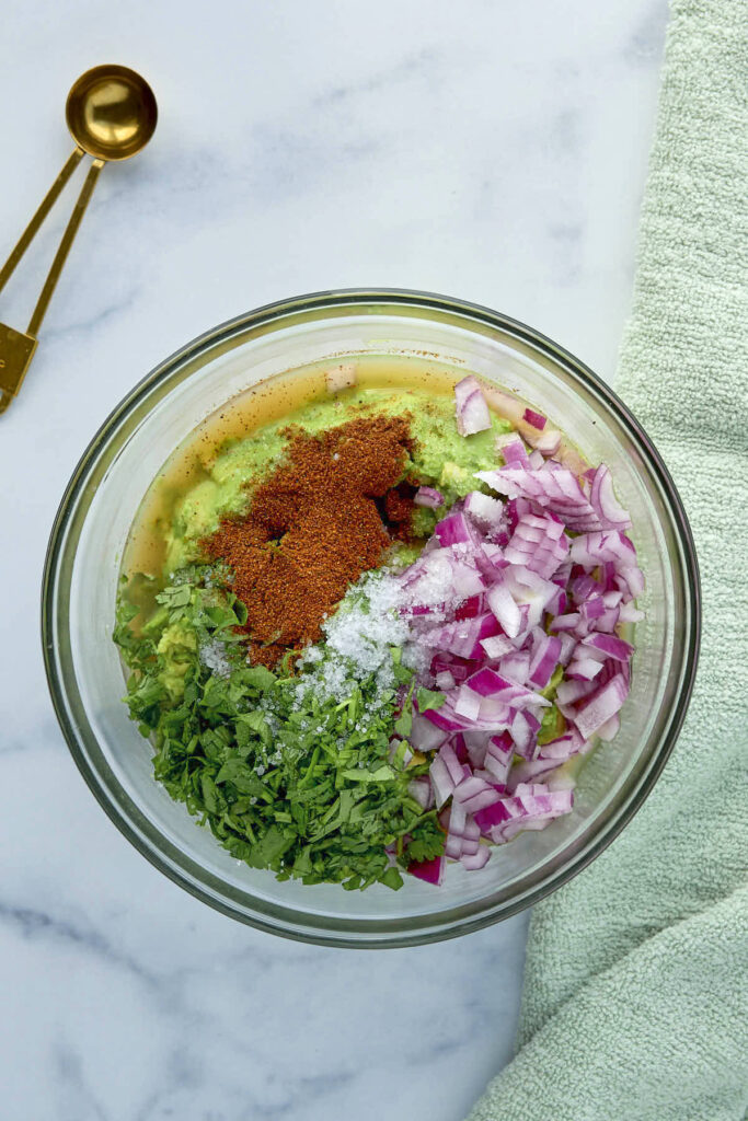 The remaining ingredients to be folded into the bowl of smashed avocado