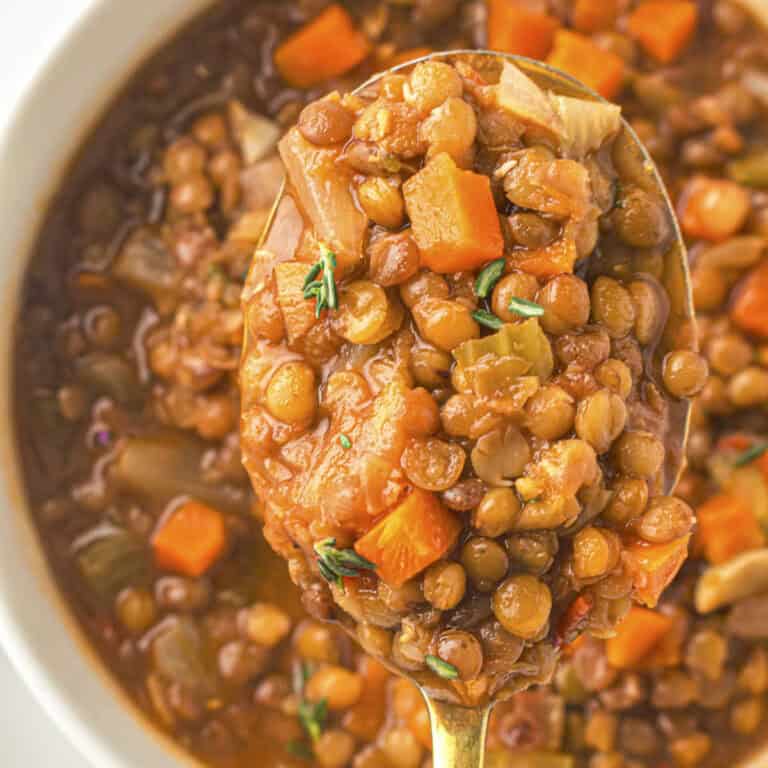 Close up shot of the lentil soup for a GLP-1 diet from this recipe, with carrots and herbs in a spoon held above the bowl