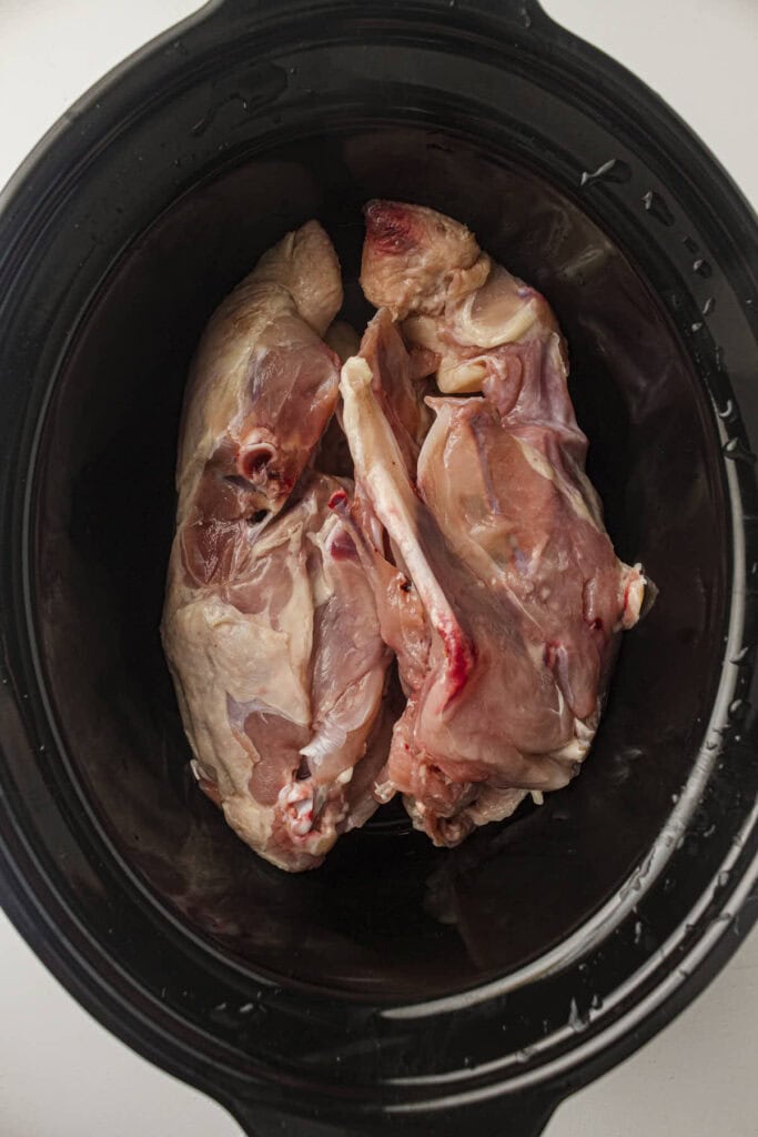 Process photo showing the uncooked chicken in the slow cooker pot